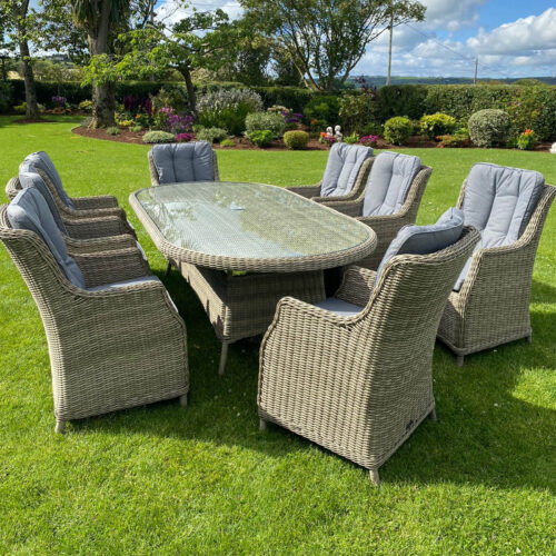 ballintoy 8 seat garden dining set with highback chairs and cushions in beige and grey and tempered glass table top in a grassy garden on a sunny day