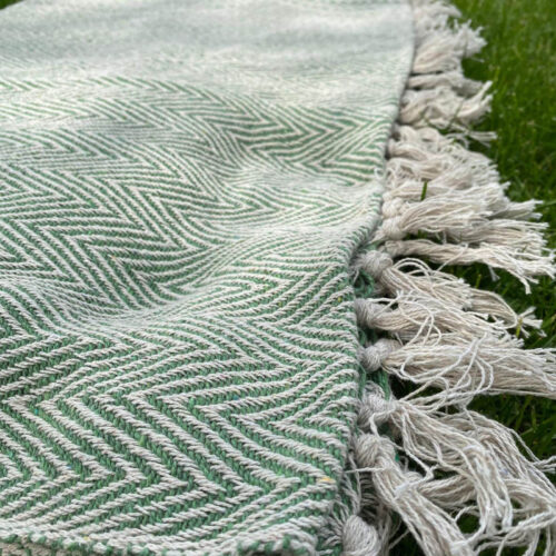 detail image of green chevron design throw or picnic blanket with cream tassel ends for living room accessories or garden furniture decoration