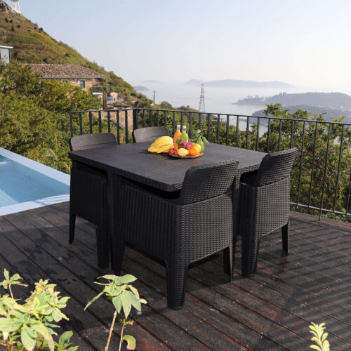black 4 seat cube dining set with rattan effect made from polypropylene with stackable and folding chairs on a wooden decking poolside
