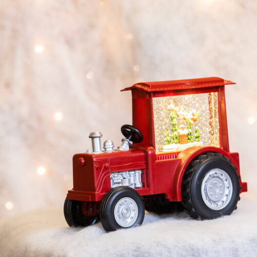 Santa red christmas tractor spinner decoration with light up and muscial snow globe effect and santa in the window for christmas display in a snowy background