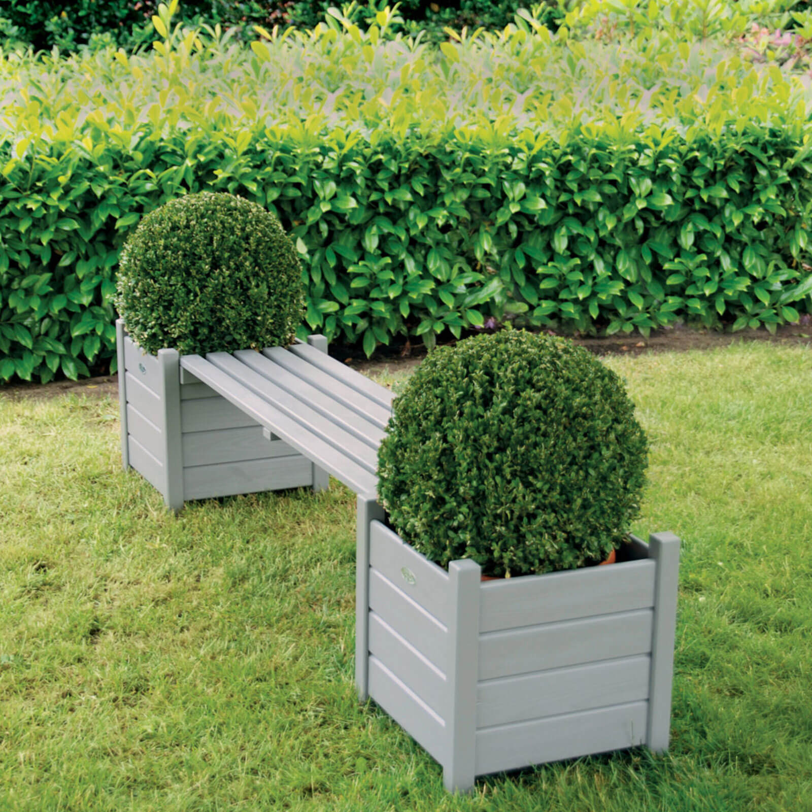 grey wooden planter bridge bench with two planters at each end of the bench displayed in a grass garden