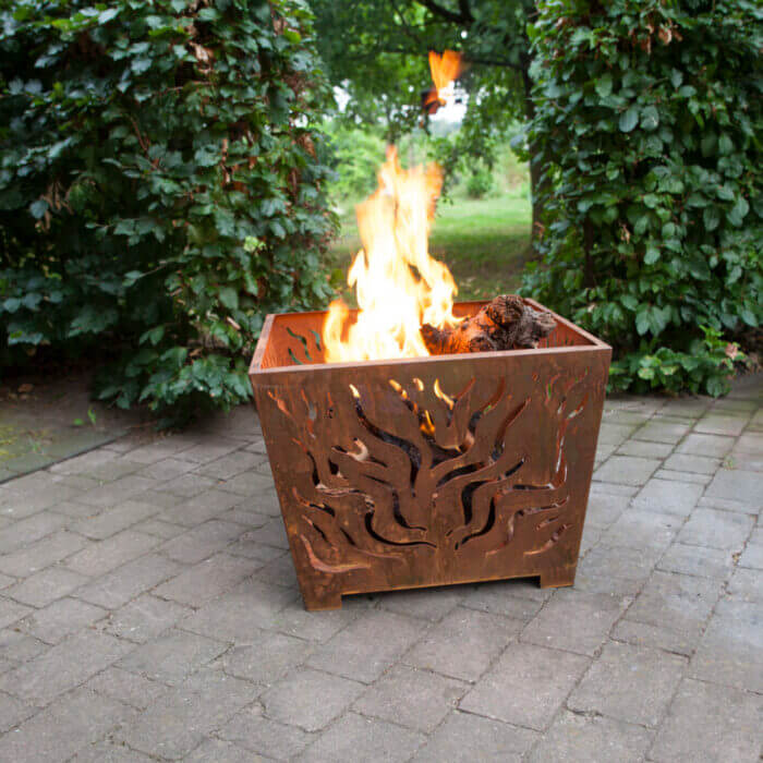 rustic bronze fire basket with laser cut design to light a fire in your garden or outdoor camping displayed with a lit fire in a garden setting