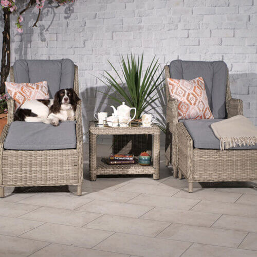 Ballintoy 2 seat companion set with 2 high back recliner armchairs with 2 footstools and a small coffee table in beige rattan and grey cushions in a patio setting