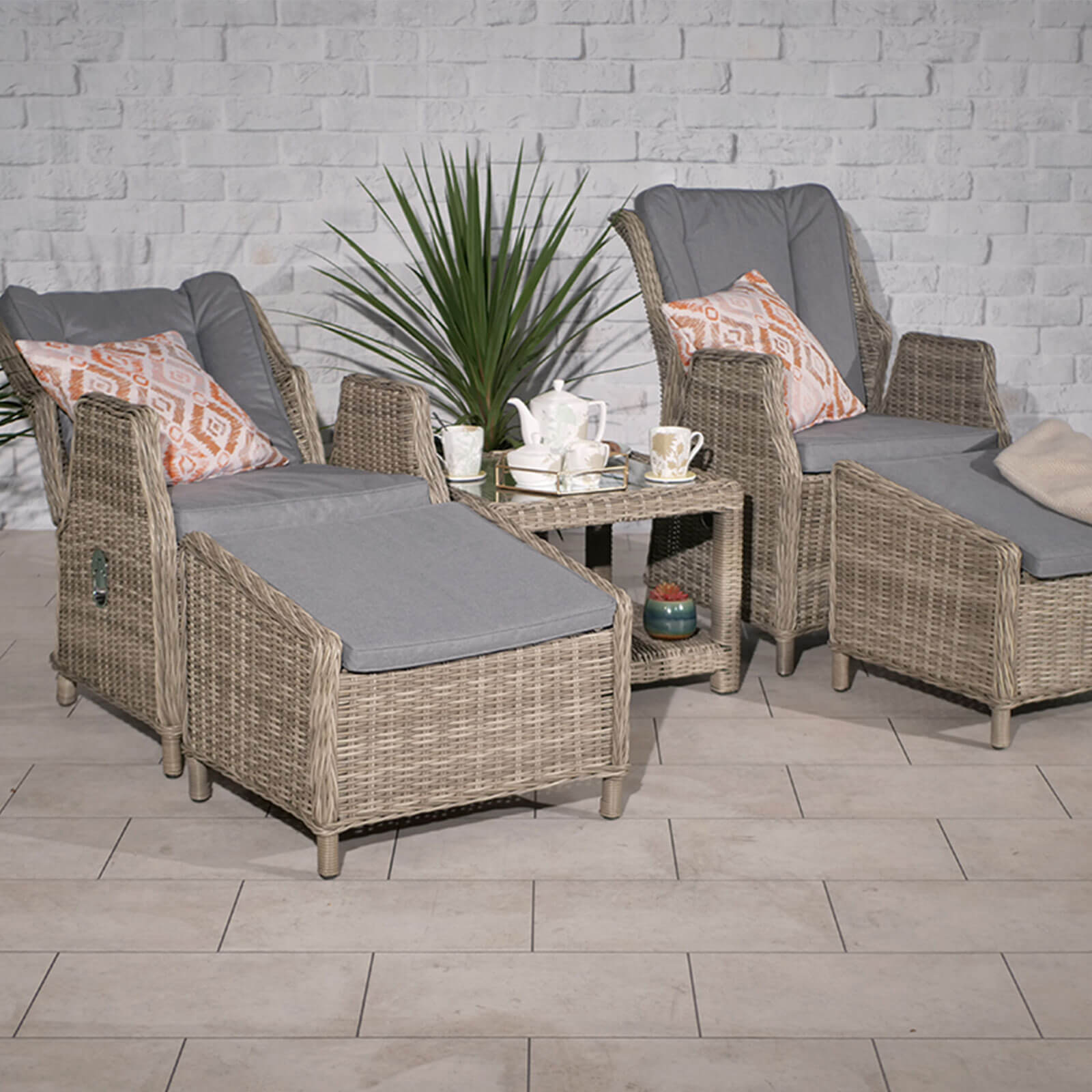 Ballintoy 2 seat companion set with 2 high back recliner armchairs with 2 footstools and a small coffee table in beige rattan and grey cushions in a patio setting and chairs reclined back