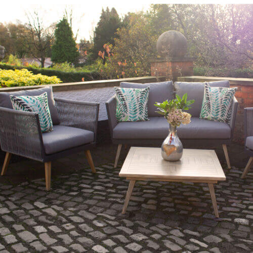 Newcastle Coffee Set with 2 armchairs and 2 seater sofa made from aluminium and grey rattan with grey cushions and small wooden coffee table displayed in a patio area